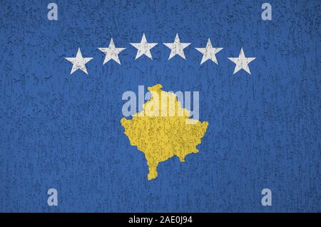 Bandiera del Kosovo raffigurato in luminosi colori di vernice su vecchi intonaci a rilievo parete vicino. Textured banner su sfondo irregolare Foto Stock