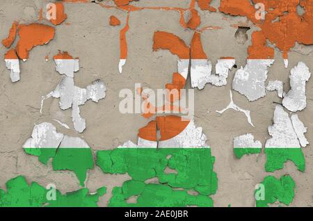 Niger bandiera raffigurata in colori di vernice sul vecchio obsoleto confuso muro di cemento vicino. Textured banner su sfondo irregolare Foto Stock