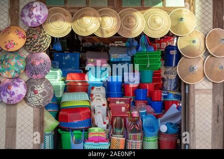 Un birmano vendita storefront conica cappelli asiatici e un ampia varietà di plastica beni domestici su una strada in un villaggio rurale in Myanmar (Birmania) Foto Stock