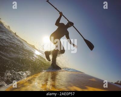 Uomo avventuroso Surfer su un dispositivo di compressione scheda è navigare nell'oceano durante una mattina di sole nella stagione autunnale. Prese a Long Beach, Tofino, Isola di Vancouver, Foto Stock