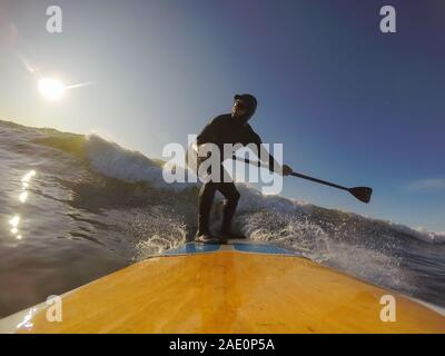 Uomo avventuroso Surfer su un dispositivo di compressione scheda è navigare nell'oceano durante una mattina di sole nella stagione autunnale. Prese a Long Beach, Tofino, Isola di Vancouver, Foto Stock