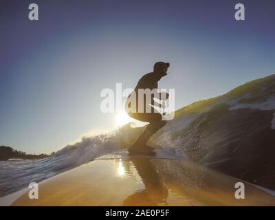 Uomo avventuroso Surfer su un dispositivo di compressione scheda è navigare nell'oceano durante una mattina di sole nella stagione autunnale. Prese a Long Beach, Tofino, Isola di Vancouver, Foto Stock