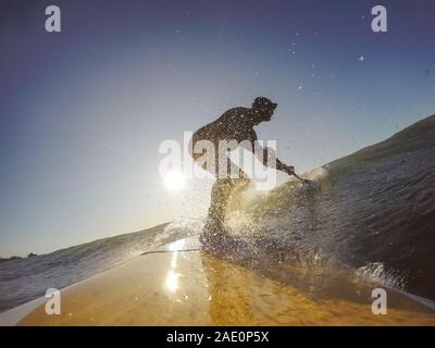 Uomo avventuroso Surfer su un dispositivo di compressione scheda è navigare nell'oceano durante una mattina di sole nella stagione autunnale. Prese a Long Beach, Tofino, Isola di Vancouver, Foto Stock