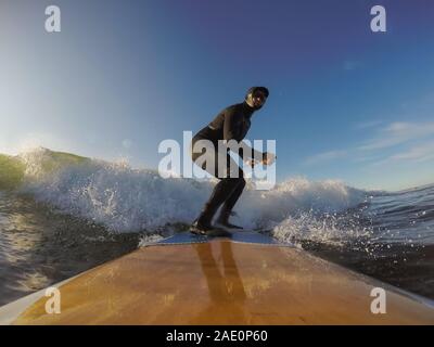 Uomo avventuroso Surfer su un dispositivo di compressione scheda è navigare nell'oceano durante una mattina di sole nella stagione autunnale. Prese a Long Beach, Tofino, Isola di Vancouver, Foto Stock