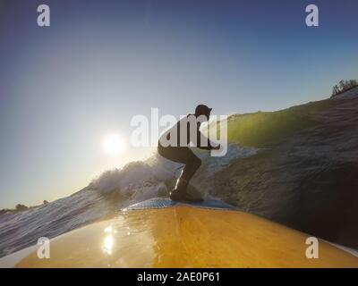 Uomo avventuroso Surfer su un dispositivo di compressione scheda è navigare nell'oceano durante una mattina di sole nella stagione autunnale. Prese a Long Beach, Tofino, Isola di Vancouver, Foto Stock