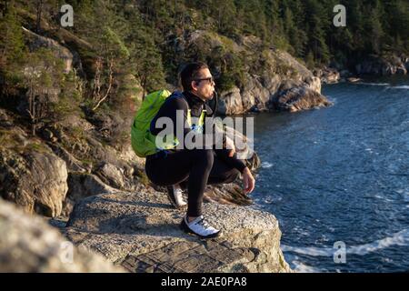 Ritratto di un avventuroso uomo latino acqua potabile al di fuori in natura durante un nuvoloso e soleggiato al tramonto. Presa faro nel parco, baia a ferro di cavallo, West Foto Stock