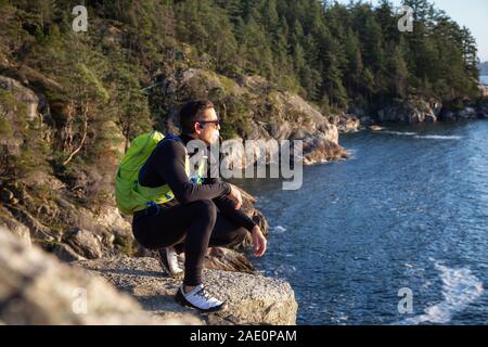 Ritratto di un avventuroso uomo latino acqua potabile al di fuori in natura durante un nuvoloso e soleggiato al tramonto. Presa faro nel parco, baia a ferro di cavallo, West Foto Stock
