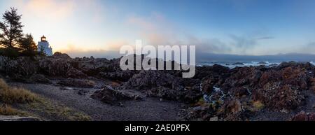 Bella vista panoramica del Rocky costa dell'Oceano Pacifico durante un colorato NUVOLOSO TRAMONTO con il faro in background. Prese su Wild Pacific Trail Foto Stock