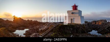 Bella vista panoramica del faro sul roccioso costa dell'Oceano Pacifico durante un colorato nuvoloso sunrise. Prese su Wild Pacific Trail in Ucluelet, Foto Stock