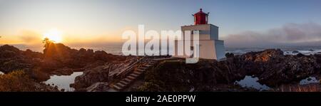 Bella vista panoramica del faro sul roccioso costa dell'Oceano Pacifico durante un colorato nuvoloso sunrise. Prese su Wild Pacific Trail in Ucluelet, Foto Stock