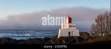 Bella vista panoramica del faro sul roccioso costa dell'Oceano Pacifico durante un colorato nuvoloso sunrise. Prese su Wild Pacific Trail in Ucluelet, Foto Stock