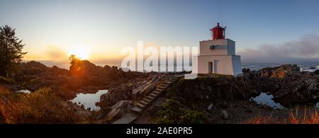 Bella vista panoramica del faro sul roccioso costa dell'Oceano Pacifico durante un colorato nuvoloso sunrise. Prese su Wild Pacific Trail in Ucluelet, Foto Stock