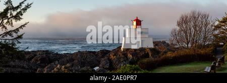 Bella vista panoramica del faro sul roccioso costa dell'Oceano Pacifico durante un colorato nuvoloso sunrise. Prese su Wild Pacific Trail in Ucluelet, Foto Stock