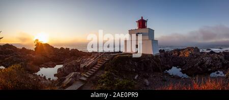 Bella vista panoramica del faro sul roccioso costa dell'Oceano Pacifico durante un colorato nuvoloso sunrise. Prese su Wild Pacific Trail in Ucluelet, Foto Stock