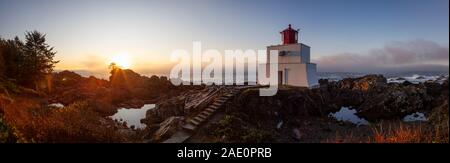 Bella vista panoramica del faro sul roccioso costa dell'Oceano Pacifico durante un colorato nuvoloso sunrise. Prese su Wild Pacific Trail in Ucluelet, Foto Stock