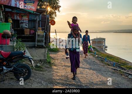 Una famiglia birmana di tre (uomo, donna e bambino sulle spalle) a casa a piedi dopo lo shopping lungo il fiume Chindwin nel nord-ovest del Myanmar (Birmania) Foto Stock