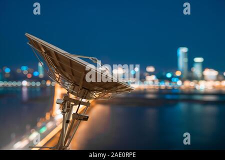 Antenna satellitare sulla sommità dell'edificio in area urbana di notte. Foto Stock
