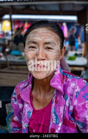 Ritratto di un adulto donna birmano in un rosa luminoso blusa con capelli scuri e con la sua faccia in polvere con thanaka, un locale & cosmetica crema solare Foto Stock