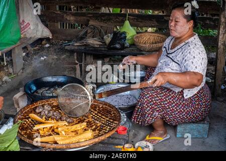 Grande villaggio donna patatine locali delizie culinarie in vendita in un mercato in Kanne villaggio lungo il fiume Chindwin nelle zone rurali del Myanmar (Birmania) Foto Stock