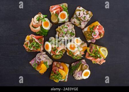 Piatto con laici smorrebrod danese panini con le pesche in scatola e le uova sulla superficie grigia Foto Stock