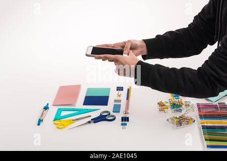 Vista ritagliata del fotografo rendendo laici piatta con forniture per ufficio commerciale per il tiro di foto sullo smartphone Foto Stock