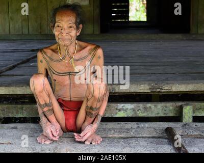 Muara Siberut, isole mentawai, Indonesia, 5 novembre 2019: Ritratto tribale uomo anziano sciamano -, con tradizionali di tatuaggi, presso la sua casa nella foresta pluviale. Foto Stock