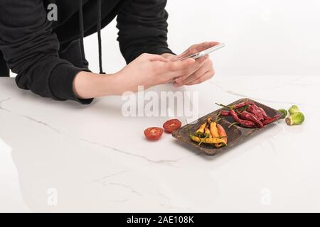 Vista ritagliata del fotografo rendendo la composizione degli alimenti per la fotografia commerciale sullo smartphone Foto Stock