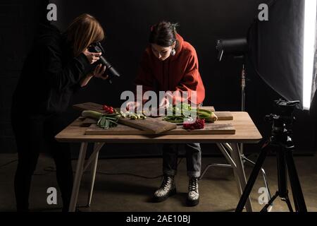 Due fotografi rendendo composizione alimentare per fotografia commerciale e prendendo foto sulla fotocamera digitale Foto Stock