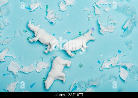Vista dall'alto di ippopotamo, di rinoceronte e di recare giocattoli con immondizia di plastica su sfondo blu, benessere animale concetto Foto Stock