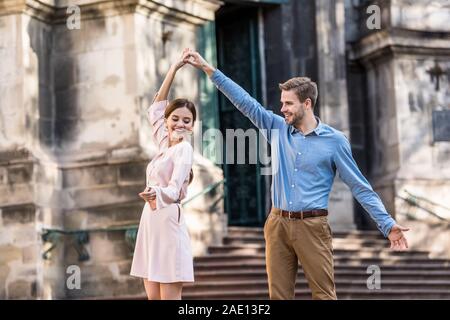 Coppia di giovani, turisti allegro danza su strada in presenza di luce solare Foto Stock