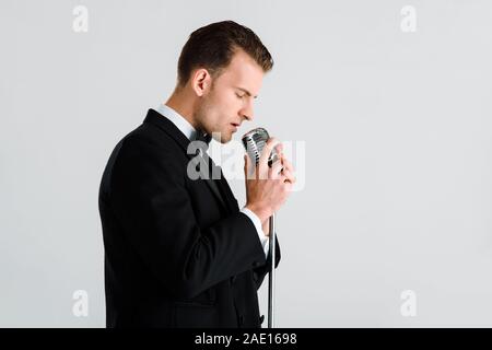 Bello il cantante di toccare il microfono retrò isolato su bianco Foto Stock