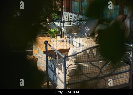 Accogliente terrazzo con divani per il riposo, il vetro con champagne su un tavolo di legno. Giornata di sole. Foto Stock