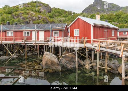 Circolo polare artico fjord cityscape con tradizionali rorbuer a stilt quay nel porto di entrata, girato sotto luce intensa, Nusfjord Falkstadoya, Lofoten, Norwa Foto Stock