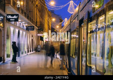 Le luci di Natale sulla strada di notte tempo con il tram ferma e lo spostamento delle persone di salire a bordo del Tram. Zagabria Croazia. Foto Stock