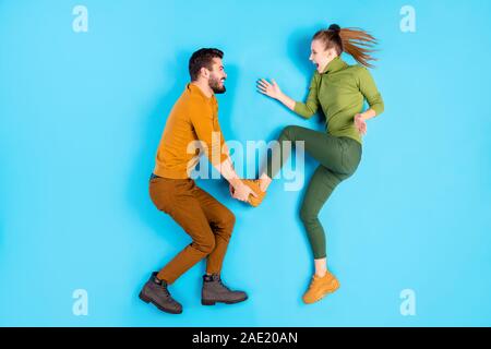 Profilo laterale superiore angolo alto guarda foto a lunghezza piena dimensione del corpo foto di crazy eccitato giocoso i coniugi con uomo prendendo piede e gettando la sua ragazza Foto Stock