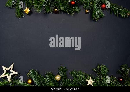 Addobbi natale (Natale baubles, stelle e poco presenta) su sfondo nero incorniciate da Abete rami Foto Stock