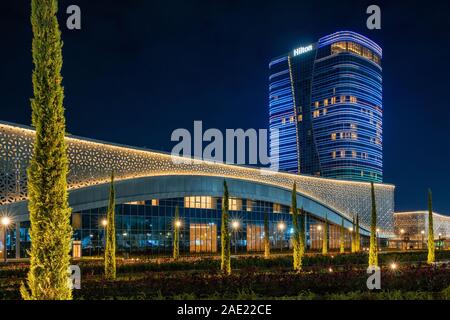 Tashkent, Uzbekistan - 30 Ottobre, 2019: sala congressi e hotel Hilton con colorati illuminazione notturna della città di Tashkent Park Foto Stock