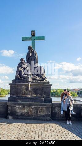 I turisti in piedi dalla statua replica del Compianto di Cristo statua della Pietà sul Ponte Carlo a Praga Repubblica Ceca. Foto Stock