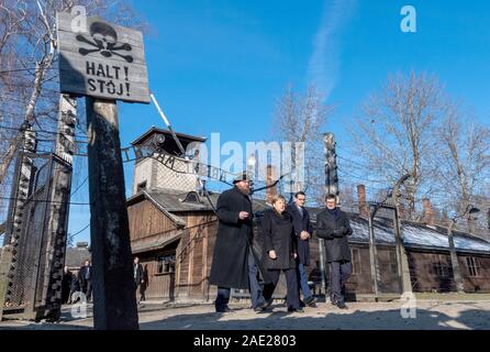 06 dicembre 2019, Polonia, Oswiecim: Cancelliere federale Angela Merkel (CDU) visite il tedesco ex campo di concentramento di Auschwitz e passeggiate sotto il cancello di ingresso con le parole "Arbeit macht frei" (Lavoro rende libero) insieme con il Primo Ministro polacco Mateusz Morawiecki (a destra di Merkel) e Piotr Cywinski (a sinistra di Merkel), Direttore del Memoriale di Auschwitz-Birkenau e Presidente della Fondazione di Auschwitz-Birkenau. Andrzej Kacorzyk, Vice Direttore del Museo di Auschwitz-Birkenau, va all'estrema destra. Merkel ha accettato un invito da parte della fondazione di Auschwitz-Birkenau, whi Foto Stock