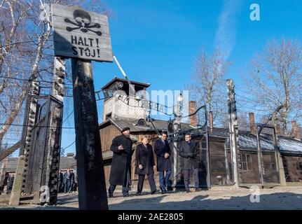 06 dicembre 2019, Polonia, Oswiecim: Cancelliere federale Angela Merkel (CDU) visite il tedesco ex campo di concentramento di Auschwitz e passeggiate sotto il cancello di ingresso con le parole "Arbeit macht frei" (Lavoro rende libero) insieme con il Primo Ministro polacco Mateusz Morawiecki (a destra di Merkel) e Piotr Cywinski (a sinistra di Merkel), Direttore del Memoriale di Auschwitz-Birkenau e Presidente della Fondazione di Auschwitz-Birkenau. Andrzej Kacorzyk, Vice Direttore del Museo di Auschwitz-Birkenau, va all'estrema destra. Merkel ha accettato un invito da parte della fondazione di Auschwitz-Birkenau, whi Foto Stock