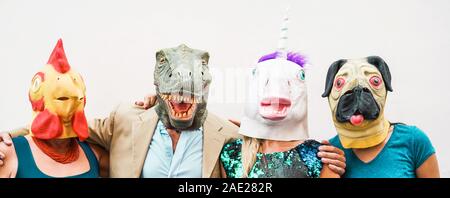 La famiglia felice di indossare diverse maschere di carnevale - crazy people divertirsi indossando sul pollo, carlino, t-rex e maschera unicorno Foto Stock
