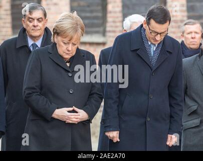 06 dicembre 2019, Polonia, Oswiecim: Cancelliere federale Angela Merkel (CDU) e Mateusz Morawiecki, Primo ministro della Polonia, prua le loro teste dopo la posa di una corona al muro della morte della ex Germania campo di concentramento di Auschwitz. Merkel ha accettato un invito da parte della fondazione di Auschwitz-Birkenau, che celebra il suo decimo anniversario con una cerimonia. Foto: Robert Michael/dpa-Zentralbild/dpa Foto Stock