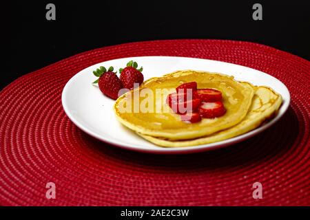 Deliziosi pancake con fragole e sciroppo nella piastra bianca Foto Stock