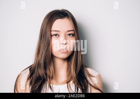 Giovane bella donna tristi e gravi in questione cercando preoccupata e riflessivo espressione facciale depressa isolato sfondo bianco in sadnes Foto Stock