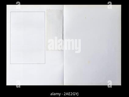 Il Libro bianco è dispiegata che mostra le pagine bianche con un telaio e un pezzo di carta usata isolata su uno sfondo nero. Foto Stock