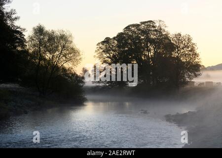 Il freddo la mattina presto sorgere del sole in una pittoresca campagna, foschia o nebbia giacente su acqua di fiume Wharfe - Burley in Wharfedale, West Yorkshire, Inghilterra, Regno Unito. Foto Stock
