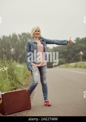 Traveler ragazza con una valigia sulla strada. Foto Stock