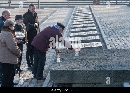 Oswiecim, Polonia. 06 Dic, 2019. Auschwitz survivor Bogdan Stanislaw Bartnikowski stabilisce una candela presso il monumento durante il Cancelliere Merkel di visitare l'ex tedesco del campo di concentramento di Auschwitz-Birkenau. Merkel ha accettato un invito da parte della fondazione di Auschwitz-Birkenau, che ha celebrato il suo decimo anniversario con una cerimonia. Credito: Robert Michael/dpa-Zentralbild/dpa/Alamy Live News Foto Stock