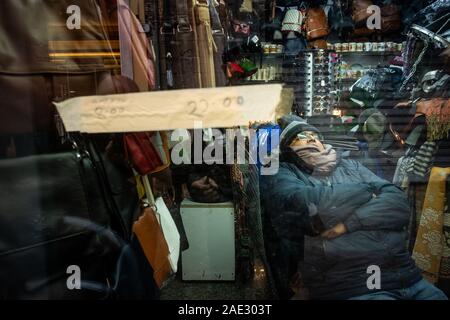 LUCCA, Italia - 24 novembre 2019: sconosciuto venditore all'interno il suo negozio addormentato prima dell'apertura del suo negozio Foto Stock