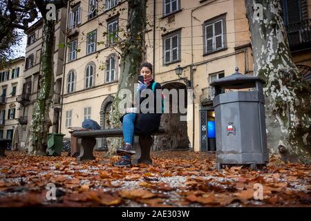 LUCCA, Italia - 24 novembre 2019: donna sconosciuta risponde al telefono mentre si sorseggia un caffè in Piazza Napoleone, comunemente denominata Piazza Grande, ho Foto Stock